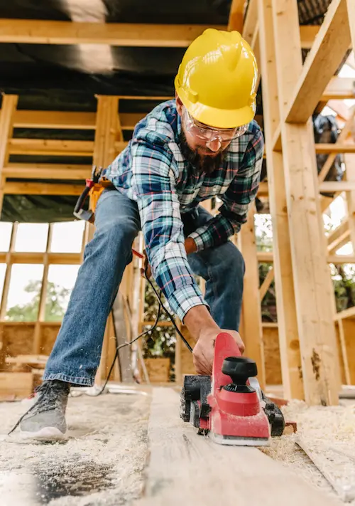 Homme en tenue de chantier travaillant à la rénovation d’une maison en construction