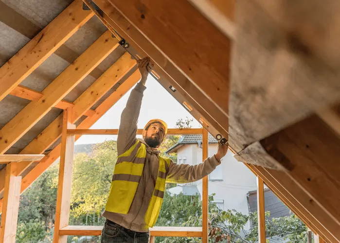 Homme en tenue de chantier installant l’isolation des combles pour améliorer la performance énergétique